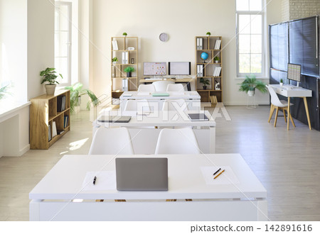 Front view of bright modern classroom with white desks, laptops and bookshelves Front view of bright modern classroom with white desks, laptops and bookshelves 142891616