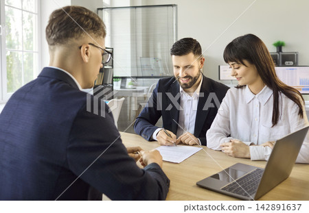 Smiling couple signing agreement with bank manager during finance consultation 142891637
