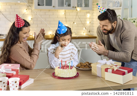 Family birthday celebration at home, happy daughter blowing out candles on cake Family birthday celebration at home, happy daughter blowing out candles on cake 142891811