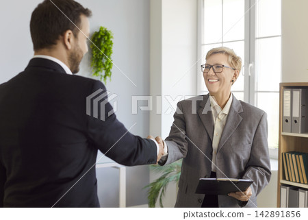 Smiling business partners handshake in office, finalizing deal and partnership Smiling business partners handshake in office, finalizing deal and partnership 142891856