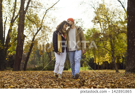 Affectionate couple strolling in fall park, cuddling amid warm colors and leaves Affectionate couple strolling in fall park, cuddling amid warm colors and leaves 142891865