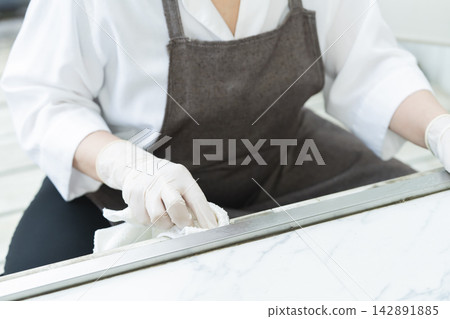 一雙女人的手正在擦拭客廳裡的各種表面。 一雙女人的手正在擦拭客廳裡的各種表面。 142891885