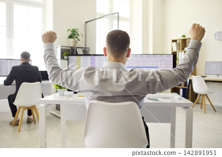 Happy businessman celebrates success at computer in bright office with spreadsheets Happy businessman celebrates success at computer in bright office with spreadsheets 142891951