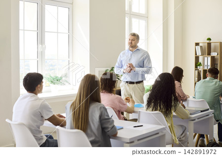 Professor leading discussion with students in classroom during college lesson Professor leading discussion with students in classroom during college lesson 142891972