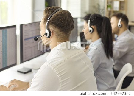 Call center operators with headsets working at computers in a modern office Call center operators with headsets working at computers in a modern office 142892362
