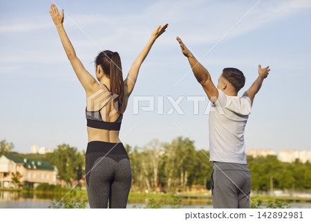 Sporty yogi people actively standing outdoors, raising arms high above head, stretching Sporty yogi people actively standing outdoors, raising arms high above head, stretching 142892981