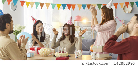 Company of friends gathering together on birthday party, clapping and blowing in party horns Company of friends gathering together on birthday party, clapping and blowing in party horns 142892986