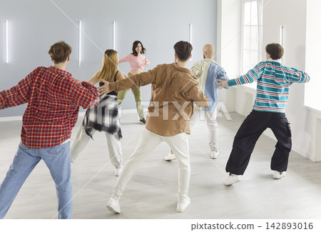 Dancing group of people actively dancing indoors, moving together with trainer in class Dancing group of people actively dancing indoors, moving together with trainer in class 142893016
