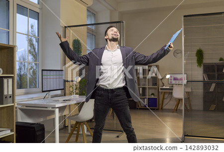 Happy businessman rejoices, arms wide, celebrating success in modern office Happy businessman rejoices, arms wide, celebrating success in modern office 142893032