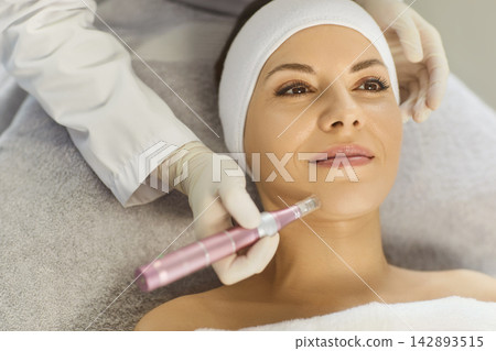 Woman lying on couch in cosmetology cabinet and receiving apparatus facial treatment procedure Woman lying on couch in cosmetology cabinet and receiving apparatus facial treatment procedure 142893515