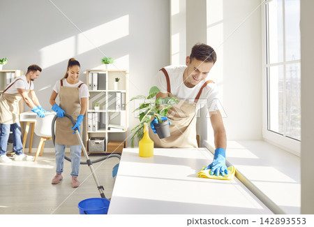 Male top performing cleaner and happy team cleaning room Male top performing cleaner and happy team cleaning room 142893553