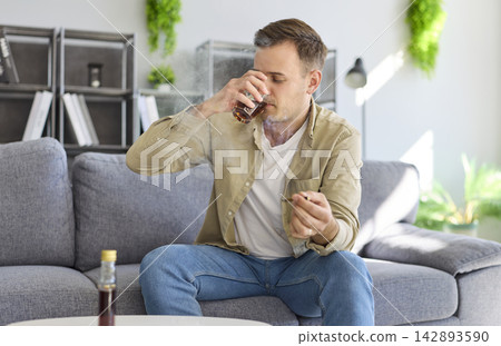 Man drinking liquor and smoking on couch, showing addiction and health harm Man drinking liquor and smoking on couch, showing addiction and health harm 142893590
