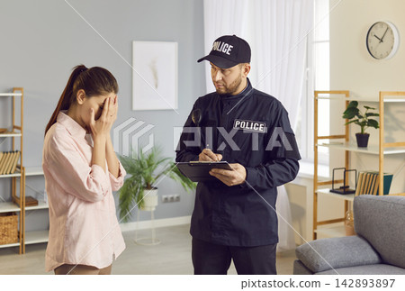 Police Officer Investigating Crime And Interviewing Crying Woman Victim At Home Police Officer Investigating Crime And Interviewing Crying Woman Victim At Home 142893897
