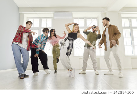 Group of excited joyful happy young friends men and women having fun together dancing indoors. 142894100