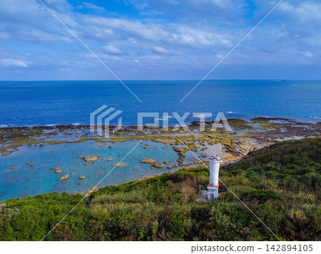 從高空俯瞰熱帶風光:一座白色燈塔矗立在蔚藍的大海和珊瑚礁的海岸線上。 從高空俯瞰熱帶風光:一座白色燈塔矗立在蔚藍的大海和珊瑚礁的海岸線上。 142894105