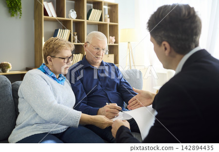 Senior couple signing contract with financial advisor during consultation at home Senior couple signing contract with financial advisor during consultation at home 142894435