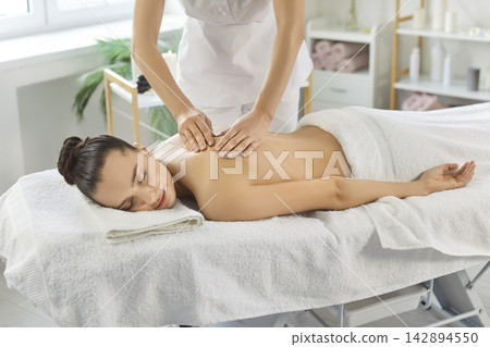 Wellness spa therapist giving relaxing back massage on table with soft towels Wellness spa therapist giving relaxing back massage on table with soft towels 142894550