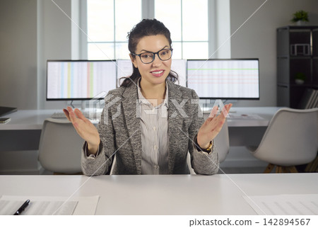 Confident businesswoman presenting on video call in bright contemporary office Confident businesswoman presenting on video call in bright contemporary office 142894567
