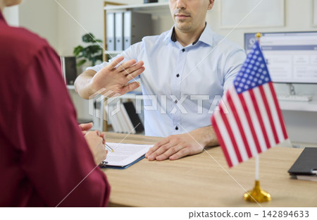 Visa interview refusal by immigration officer, stop hand gesture beside USA flag Visa interview refusal by immigration officer, stop hand gesture beside USA flag 142894633