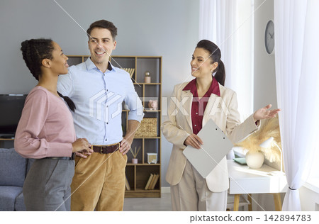 Happy couple guided by realtor during bright apartment tour and consultation Happy couple guided by realtor during bright apartment tour and consultation 142894783