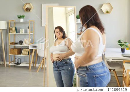 Obese woman posing in front of mirror at home wearing sporty top, chubby overweight plus size lady Obese woman posing in front of mirror at home wearing sporty top, chubby overweight plus size lady 142894829