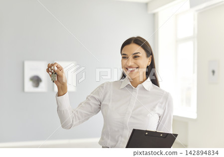 Portrait Of Happy Female Real Estate Agent Holding Keys To A New Home Portrait Of Happy Female Real Estate Agent Holding Keys To A New Home 142894834