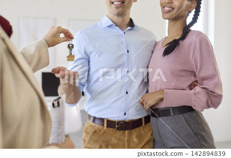 Smiling couple receives new home keys from realtor at successful property closing Smiling couple receives new home keys from realtor at successful property closing 142894839
