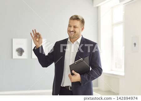 Portrait Of Happy Male Realtor Holding Keys To New Home Or Office Portrait Of Happy Male Realtor Holding Keys To New Home Or Office 142894974