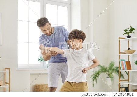 Dad happy training son, karate with cute little boy, learning martial arts at home, playful cheerful Dad happy training son, karate with cute little boy, learning martial arts at home, playful cheerful 142894991