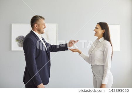 Real Estate Agent Handing Keys To A Happy Client From New Home Real Estate Agent Handing Keys To A Happy Client From New Home 142895060