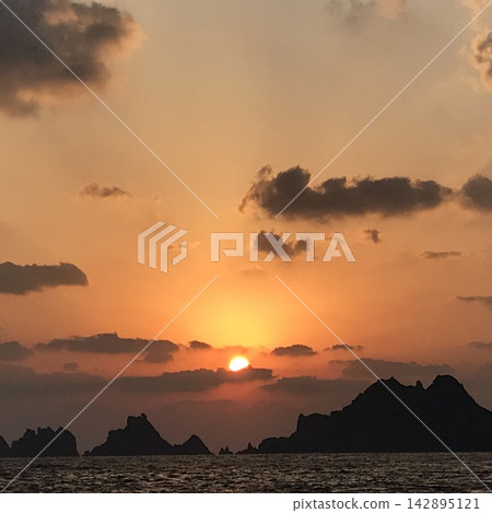 夕陽西下,沉入小島背後,但仍在用盡最後的力氣閃耀著光芒。 夕陽西下,沉入小島背後,但仍在用盡最後的力氣閃耀著光芒。 142895121