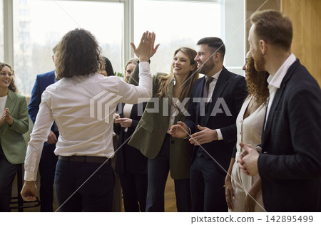 Diverse business team celebrating success with high five during office meetup Diverse business team celebrating success with high five during office meetup 142895499