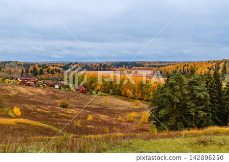 Autumn landscape with colorful foliage and small village in the distance Autumn landscape with colorful foliage and small village in the distance 142896250