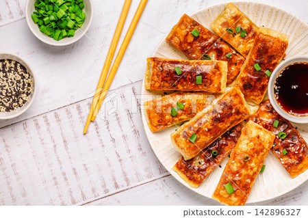 Dumplings are arranged on a plate with a small bowl of dipping sauce Dumplings are arranged on a plate with a small bowl of dipping sauce 142896327
