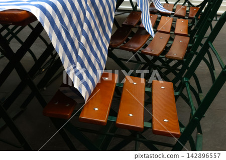 Striped Tablecloth on Wooden Folding Chairs in Outdoor Cafe Setting Striped Tablecloth on Wooden Folding Chairs in Outdoor Cafe Setting 142896557
