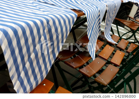 Blue and White Striped Tablecloths on Wooden Outdoor Seating for Cafes and Restaurants Blue and White Striped Tablecloths on Wooden Outdoor Seating for Cafes and Restaurants 142896800