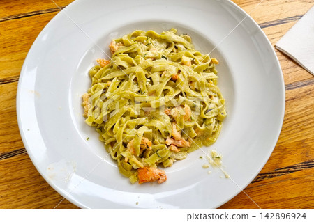 Delicious Plate of Fresh Spinach Fettuccine Pasta with Salmon on Wooden Table Delicious Plate of Fresh Spinach Fettuccine Pasta with Salmon on Wooden Table 142896924