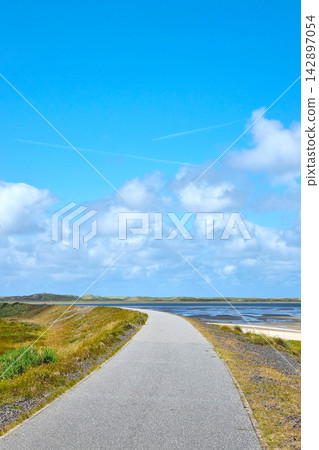Scenic Coastal Pathway under Vibrant Blue Sky: Tranquility and Adventure 142897054
