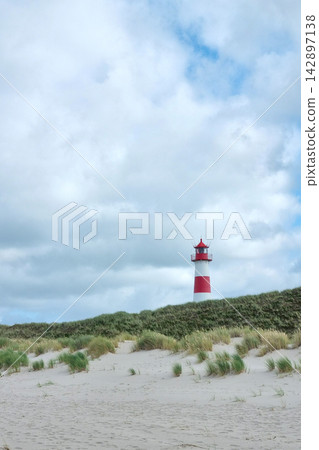 Scenic Coastal Landscape with Iconic Red and White Lighthouse in Tranquil Setting Scenic Coastal Landscape with Iconic Red and White Lighthouse in Tranquil Setting 142897138
