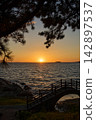 [Nishiura Coast] The silhouette of the pedestrian bridge against the sunset sinking below the horizon. 142897537