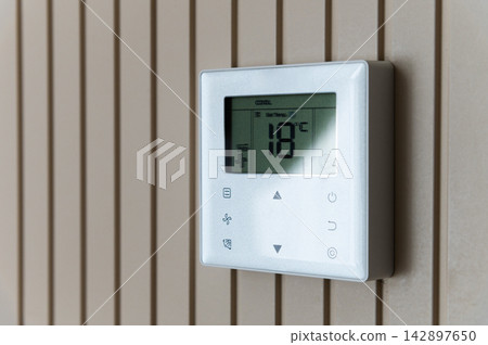 Digital Climate Control Thermostat Mounted On Slatted Wall 142897650