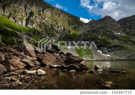 Mountain lake with rocky shore and steep cliffs Mountain lake with rocky shore and steep cliffs 142897725