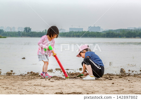 Children Playing with Sand and Water Tools on the Beach, Kids Exploring Muddy Shoreline, Sensory Play and Nature Discovery Children Playing with Sand and Water Tools on the Beach, Kids Exploring Muddy Shoreline, Sensory Play and Nature Discovery 142897802