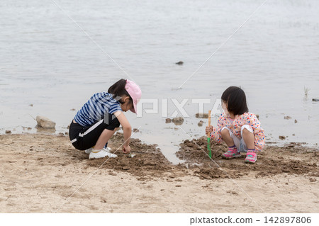 Children Playing with Sand and Water Tools on the Beach, Kids Exploring Muddy Shoreline, Sensory Play and Nature Discovery Children Playing with Sand and Water Tools on the Beach, Kids Exploring Muddy Shoreline, Sensory Play and Nature Discovery 142897806