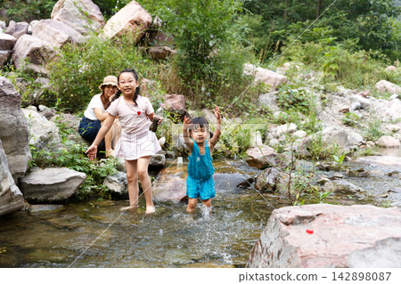 Happy family playing in the clear mountain river during summer trip Happy family playing in the clear mountain river during summer trip 142898087