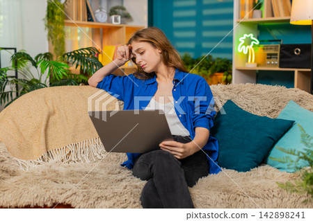 Young woman on home sofa seeing laptop error or rejection feeling upset during remote work problem Young woman on home sofa seeing laptop error or rejection feeling upset during remote work problem 142898241