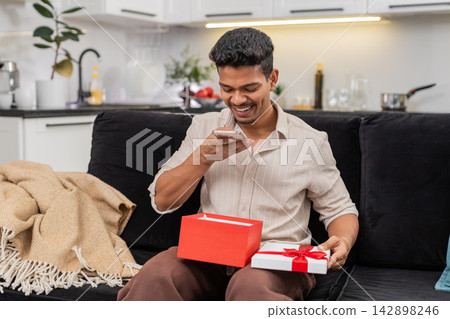 Indian man opens gift box surprised takes smartphone photo thanks friends for present with big smile 142898246