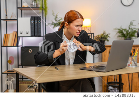 Young businesswoman reacts to report mismatch on laptop crushes paper angrily and fears audit ahead Young businesswoman reacts to report mismatch on laptop crushes paper angrily and fears audit ahead 142898313