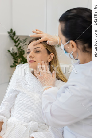 Caucasian young woman facial skin check by cosmetologist doctor before cosmetic procedure in clinic Caucasian young woman facial skin check by cosmetologist doctor before cosmetic procedure in clinic 142898466
