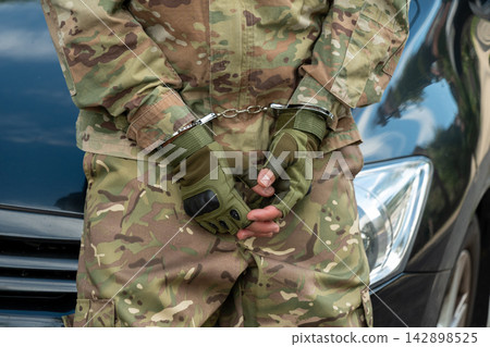 Detained serviceman in handcuffs standing in front of car Detained serviceman in handcuffs standing in front of car 142898525